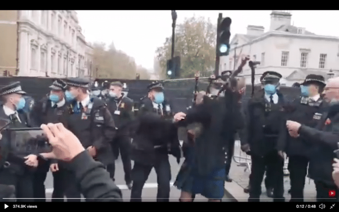 Police officer pushes piper to the ground near Cenotaph